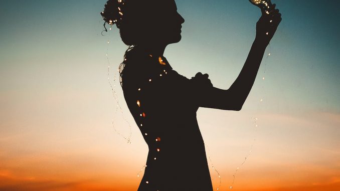 woman holding lit up light string silhouette photography