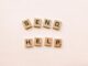 scrabble tiles spelling send help on pink
